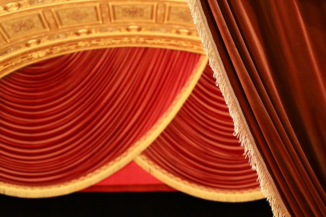 Ornate theatre stage curtains under warm light